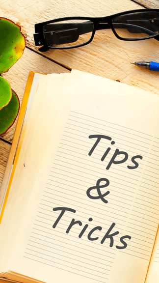 Image montrant un carnet sur un bureau, avec les mots Tips & Tricks inscrits, ainsi qu'une plante succulente, une paire de lunettes et un stylo bleu